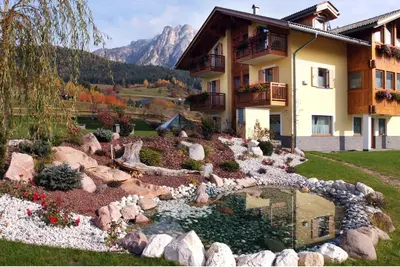 a garden in front of a house with a pond at Agritur Maso Chemela in Cavalese