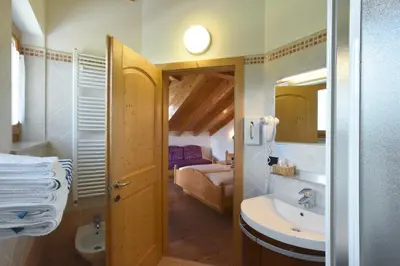 a bathroom with a sink and a toilet and a bedroom at Agritur Maso Chemela in Cavalese