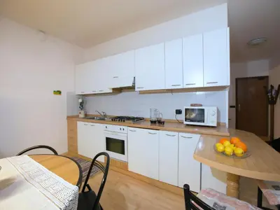 a kitchen with white cabinets and a wooden table at Apartment in Predazzo near Dolomiti Superski in Predazzo