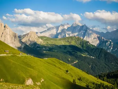 a green hill with mountains in the background at Apartment in Predazzo near Dolomites Trails in Predazzo