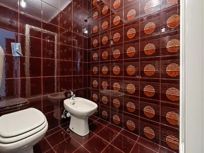 a bathroom with a toilet and a tiled wall at Apartment in Predazzo near Dolomites Trails in Predazzo
