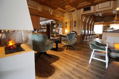 a living room with a fireplace and chairs at Astor Suites B&B in Selva di Val Gardena