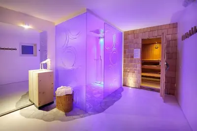 a purple bathroom with a refrigerator and a walk in shower at Astor Suites B&B in Selva di Val Gardena