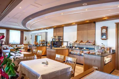 a restaurant with tables and chairs and a kitchen at Astor Suites B&B in Selva di Val Gardena