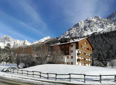 a building in the snow with mountains in the background at Botton d'oro in Borca di Cadore