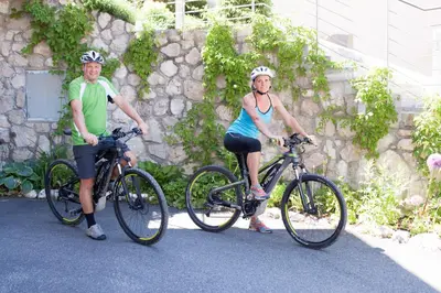 two people on bikes parked next to a stone wall at Antorè in Badia