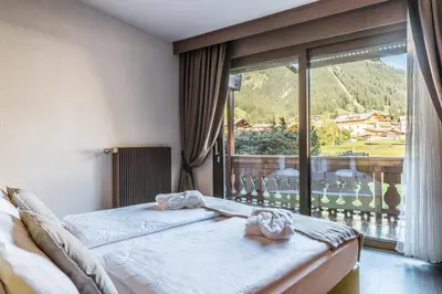 a bedroom with a bed and a large window at Residence Anda in Pozza di Fassa