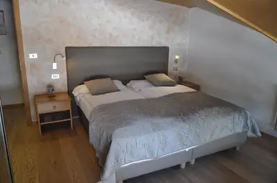 a bedroom with a large bed and a side table at Residence Anda in Pozza di Fassa