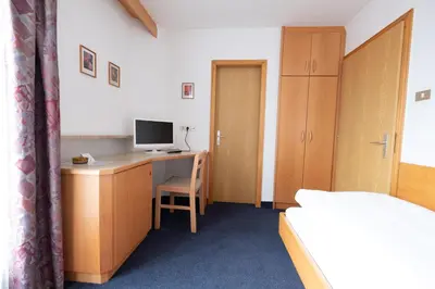 a bedroom with a desk with a computer and a bed at Garni Volgger in Brunico