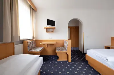 a room with two beds and a desk and a tv at Garni Volgger in Brunico
