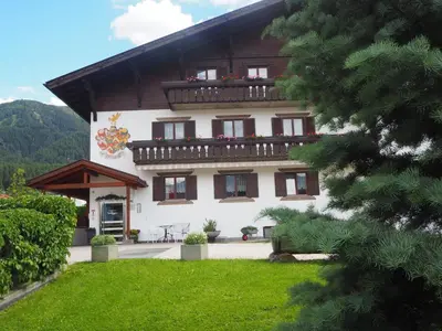 a large white building with a balcony and a yard at Garni Volgger in Brunico