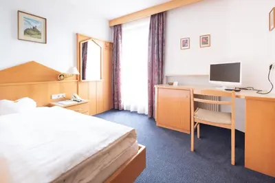 a hotel room with a bed and a desk with a computer at Garni Volgger in Brunico