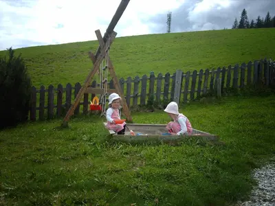 two children playing in a sandbox in the grass at Ferienwohnung Winklerhof in Maranza