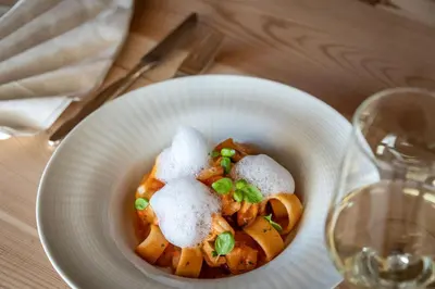 a white bowl of food on a table with a glass of wine at Tirolerhof guesthouse in Naz-Sciaves