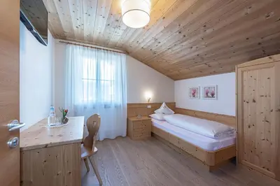a bedroom with a bed and a desk and a window at Tirolerhof guesthouse in Naz-Sciaves
