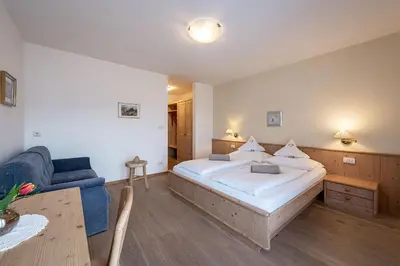 a bedroom with a large bed and a blue couch at Tirolerhof guesthouse in Naz-Sciaves