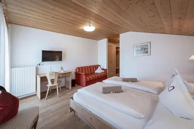 a hotel room with two beds and a desk at Tirolerhof guesthouse in Naz-Sciaves