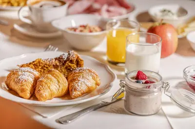 a breakfast table with a plate of croissants and milk at Hotel Edda in Selva di Val Gardena