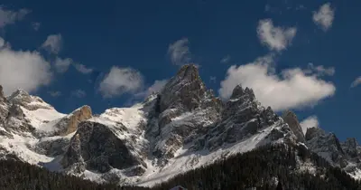 a snow covered mountain range with clouds in the sky at Hotel Paladin in San Martino di Castrozza