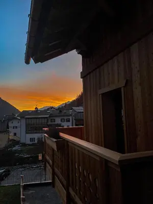 a wooden building with the sunset in the background at Cesa Prinoth in Campitello di Fassa