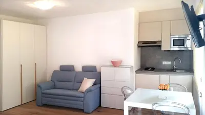 a living room with a blue chair and a kitchen at Traubenhof in Magrè allʼ Adige