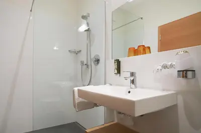 a white bathroom with a sink and a shower at Schiessstandhof in Montagna