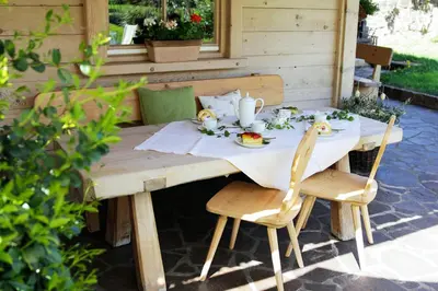 a wooden table with chairs and a white table cloth at Schiessstandhof in Montagna