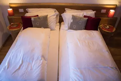two beds in a room with white sheets and pillows at Residence Valpiccola in Val di Zoldo