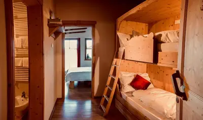 a room with two bunk beds and a bathroom at Residence Valpiccola in Val di Zoldo