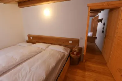 a bedroom with a large bed with a wooden headboard at Residence Valpiccola in Val di Zoldo