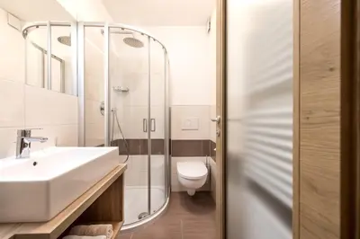 a bathroom with a sink and a shower and a toilet at Niederhof life in Lana