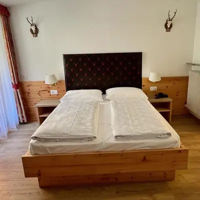 a bed in a bedroom with two nightstands and two lamps at Zur Brücke apartments and rooms - Your home in heart of South Tyrol, with Brixencard in Fortezza