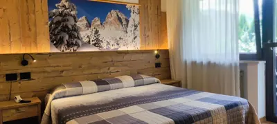 a bedroom with a bed and a wooden wall at Hotel Miramonti in Vigo di Fassa
