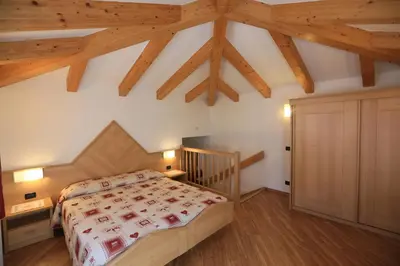 a bedroom with a bed and a wooden ceiling at Hotel Miramonti in Vigo di Fassa