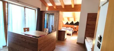 a living room with a desk and a bedroom at Hotel Miramonti in Vigo di Fassa