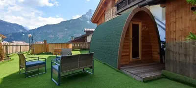 a gazebo with two chairs and a bench in a yard at Hotel Miramonti in Vigo di Fassa