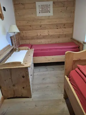 a room with two beds and a desk in a room at Maso Pinterato in Cavalese