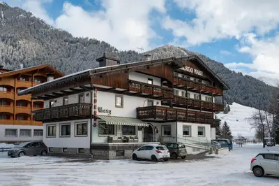 a dining room with tables and chairs and windows at Hotel Mary in Pozza di Fassa
