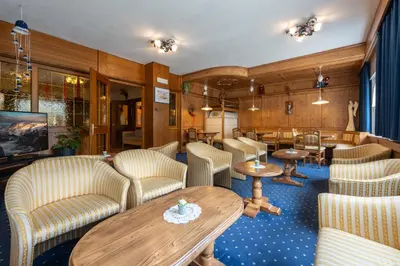 a dining room with a table and chairs and a clock at Hotel Mary in Pozza di Fassa