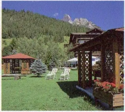 a group of white chairs in a yard with a building at Hotel Mary in Pozza di Fassa
