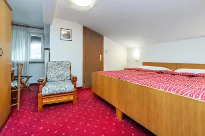 a bedroom with a large bed and a chair at Hotel Mary in Pozza di Fassa