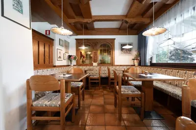 a living room with chairs and a table and a television at Hotel Mary in Pozza di Fassa