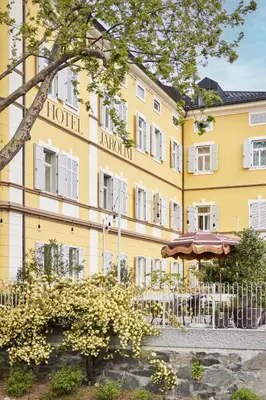 a yellow hotel with an umbrella in front of it at Hotel Jarolim in Bressanone