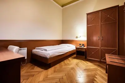 a small bedroom with a bed and a cabinet at Hotel Jarolim in Bressanone