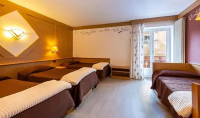 a hotel room with three beds and a window at Hotel La Serenella in Moena
