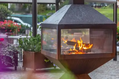 a fireplace in a courtyard with a fire pit at Hotel La Serenella in Moena