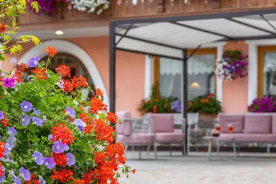 a group of chairs and flowers in front of a building at Hotel La Serenella in Moena