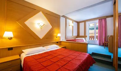 a hotel room with a bed with a red blanket at Hotel La Serenella in Moena