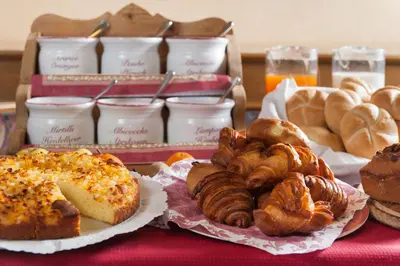 a table topped with different types of pastries and bread at Hotel La Serenella in Moena