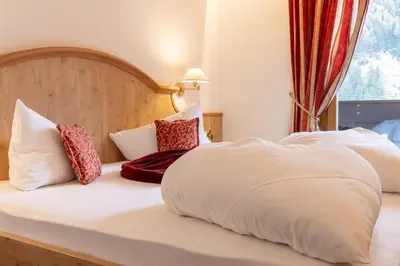 a bedroom with a bed and a desk and a table at Hotel Erna in Colle Isarco